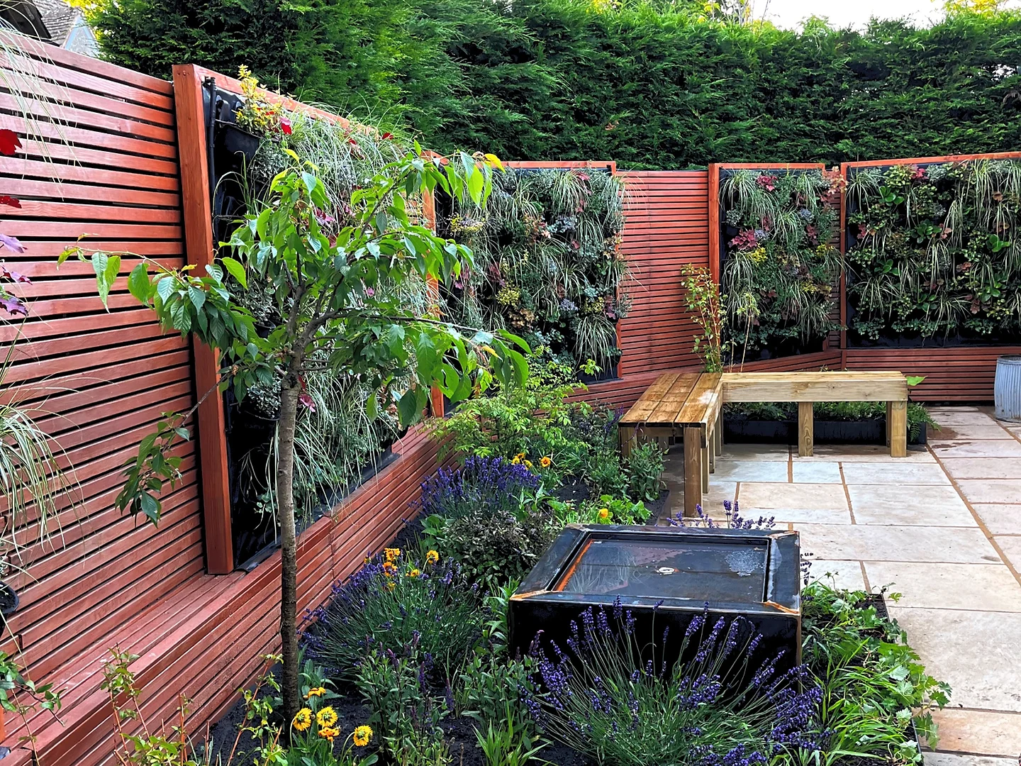 Cotswold cottage courtyard garden with a living wall, built-in bench and dark slate water feature